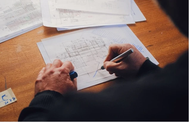 Arquiteto a desenhar plantas de arquitetura sobre secretária